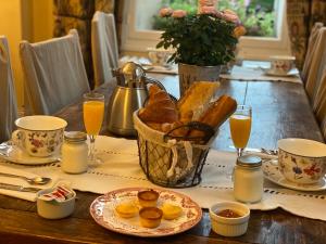 a table with a basket of bread and glasses of orange juice at Manoir de la Marjolaine in Cabourg