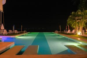 una piscina por la noche con sillas y palmeras en Le Divine Comedie Beach Resort, en Baan Tai