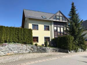 a house with a stone wall and a tree at Ferienwohnung Heike Strobel in Schwarzenberg