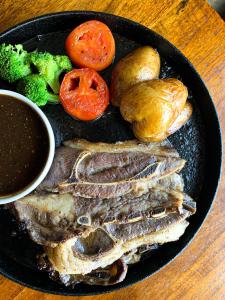 ein Teller mit Fleisch und Gemüse auf dem Tisch in der Unterkunft Lazenda Hotel in Labuan