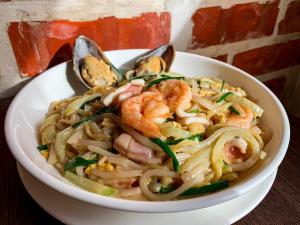 a bowl of pasta with shrimp and vegetables in it at Lazenda Hotel in Labuan
