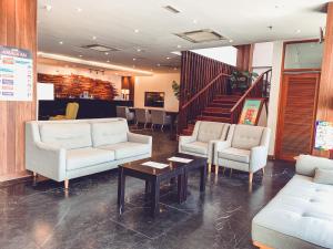 eine Lobby mit Sofas, einem Tisch und einer Treppe in der Unterkunft Lazenda Hotel in Labuan
