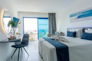 a bedroom with a bed and a desk with a view of the ocean at Anonymous Beach Hotel (Adults 16+) in Ayia Napa