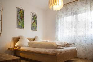 Schlafzimmer mit einem Bett mit einem Fenster und einem Kronleuchter in der Unterkunft Bio-Ferienhaus Newergarten in Wadern