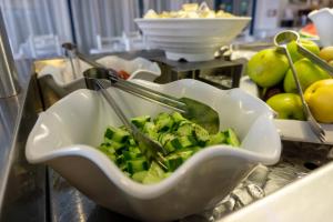 a bowl of food with tongs and broccoli on a counter at Anonymous Beach Hotel (Adults 16+) in Ayia Napa