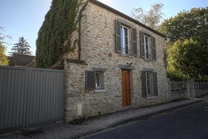 a brick house with a red door on a street at Chez Oscar in Barbizon