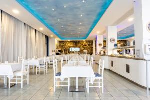 a restaurant with white tables and chairs and a blue ceiling at Anonymous Beach Hotel (Adults 16+) in Ayia Napa