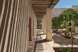 um corredor de um edifício com uma árvore e mesas em Kedma by Isrotel Design em Sede Boqer