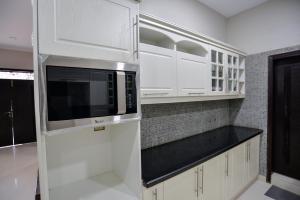 a kitchen with white cabinets and a microwave at Hillside Homes in Karachi