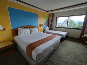 a hotel room with two beds and a window at Sing Golden Place Hotel in Hat Yai