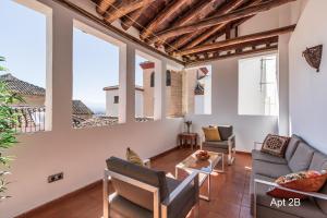 a living room with a couch and chairs and windows at San José Apartments in Granada