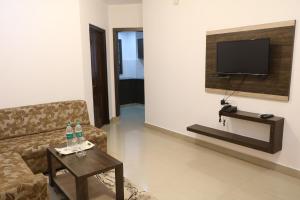 a living room with a couch and a table and a television at FLORA SUITES in Bangalore