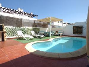una piscina en un patio con sillas y mesa en La Fresa Hostel en Corralejo
