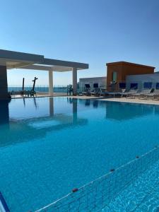 a large swimming pool with blue water and chairs at Hotel Bar Restaurant Triumf Shengjin in Shëngjin
