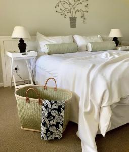 a bedroom with a large white bed with a basket at Coral Tree Colony Bed & Breakfast in Southbroom
