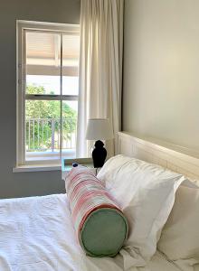 ein Bett mit einem Kissen und einem Fenster in der Unterkunft Coral Tree Colony Bed & Breakfast in Southbroom