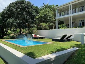 a swimming pool with a fountain in the yard of a house at Coral Tree Colony Bed & Breakfast in Southbroom