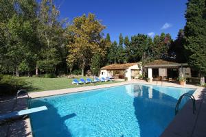 a swimming pool with blue chairs and a house at El Bikoro in Port de Pollensa