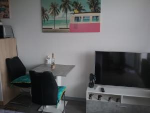 sala de estar con TV de pantalla plana, mesa y sillas en Home from Home, en Wiebelskirchen