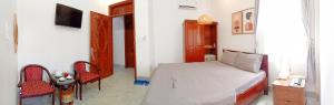 a bedroom with a bed and two chairs and a television at HOTEL DUY NHẤT 2 in Phú Nhơn