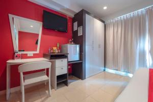 a bedroom with a red wall with a desk and a mirror at Access Inn Pattaya in Pattaya Central