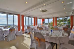 un salón de banquetes con mesas y sillas blancas y ventanas en Centauria Lake Resort, en Embilipitiya