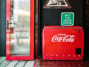 an old coca cola cooler sitting in front of a door at PitStop Lodge in Gordonʼs Bay