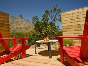 高登灣的住宿－PitStop Lodge，一个带两张红色椅子和一张桌子的庭院,并享有山景。