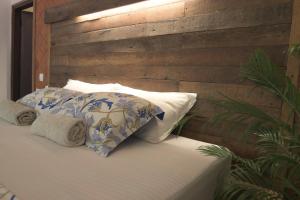 1 dormitorio con pared de madera y cama con almohadas en InDa hotel en Varkala