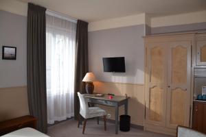 una camera d'albergo con scrivania e finestra di Hotel Ajoncs d'Or a Saint Malo