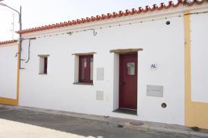 un edificio blanco con puerta roja y ventanas en Casa da Orada, en Outeiro