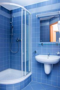 a blue tiled bathroom with a shower and a sink at Ziemowit in Jarnołtówek