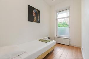 a white room with a bed and a window at Canal view apartment with private balcony in Amsterdam