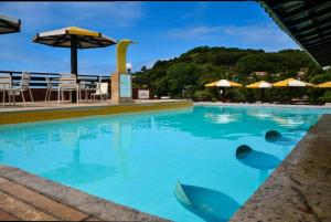 a swimming pool with blue water and umbrellas at Pipa's Ocean - Flat Vista Mar in Pipa