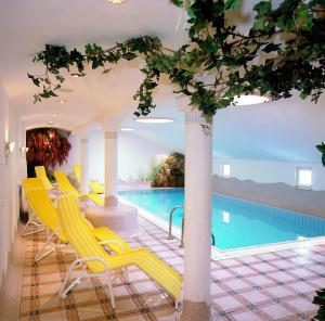 ツァウヘンゼーにあるHotel Enzian by Alpeffect Hotelsの黄色い椅子とスイミングプールが備わるプールです。