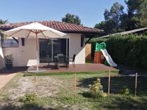 een huis met een paraplu en een speeltuin bij Gîte l'Escapade au bassin d'Arcachon à Biganos in Biganos