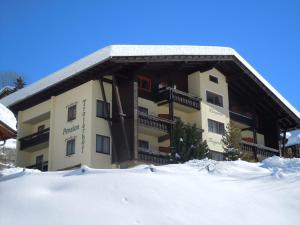 un gran edificio con nieve delante en Pension Trojerhof, en Heiligenblut