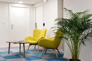 zwei gelbe Stühle, ein Tisch und eine Topfpflanze in der Unterkunft Résidence La Canopée in Straßburg