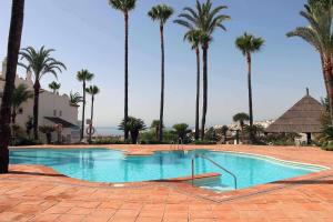 een zwembad met palmbomen in een resort bij Fuente Duquesa in San Luis de Sabinillas