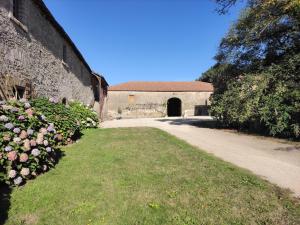 un bâtiment en pierre avec un chemin et des fleurs dans l'établissement Château du Parc Soubise en Vendée, à Mouchamps