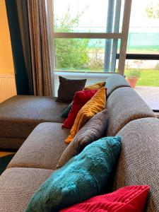 ein Haufen Kissen auf einer Couch vor einem Fenster in der Unterkunft Appart HautsSarts in Liers