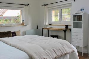 a bedroom with a bed and a desk and windows at Le Chemin du Village in Croth