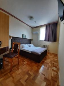 um quarto com uma cama, uma cadeira e uma televisão em Hotel & Restaurant Great Wall em Sarajevo