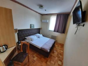 a bedroom with a bed and a television and a chair at Hotel & Restaurant Great Wall in Sarajevo