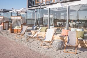 eine Gruppe von Stühlen und Sonnenschirmen am Strand in der Unterkunft Strandgut Resort in Sankt Peter-Ording