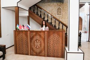 una mujer está de pie detrás de un podio en una casa en Boutique hotel Shakh, en Bukhara