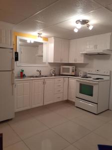 a kitchen with white cabinets and white appliances at Appartement Bellevue in Saint-Félicien