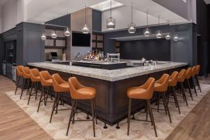 a bar with orange bar stools in a room at Hyatt Centric Downtown Minneapolis in Minneapolis