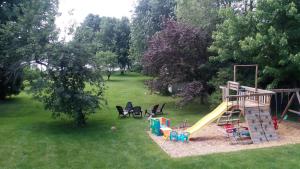 um parque infantil com escorrega e cadeiras na relva em Appartement Bellevue em Saint-Félicien