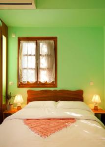 a bedroom with a bed with a green wall and a window at Victoria's Guesthouse in Damouchari